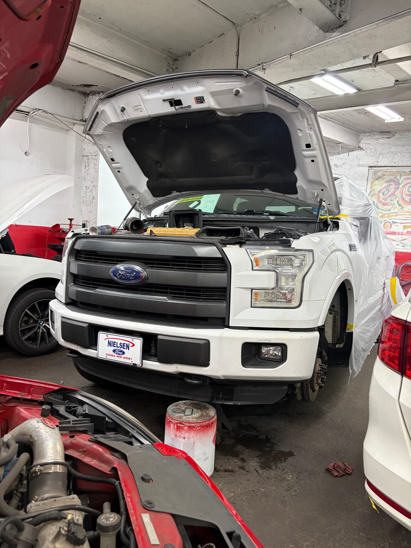 Ford F-150 with the hood open and front-end panels being fitted